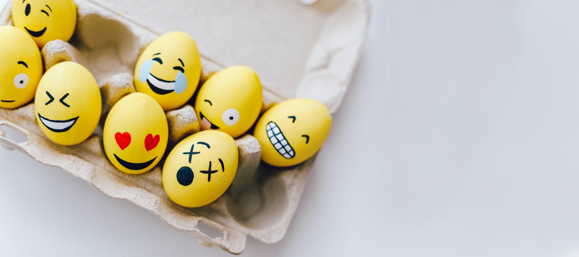 Eggs painted with different emoji faces in a carton, the range of customer emotions a customer journey map captures.