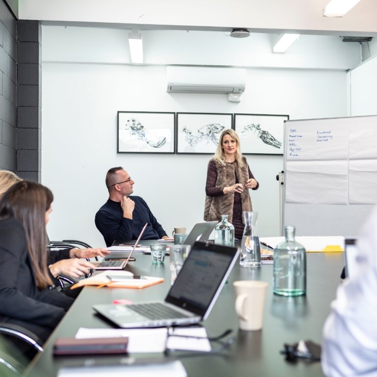 Facilitator presenting at a whiteboard to a small group of business owners at a Good CX workshop